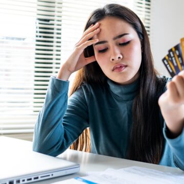 unhappy-girl-holding-three-credit-cards-feeling-s-2025-01-29-02-45-42-utc A woman looks stressed over her credit cards
