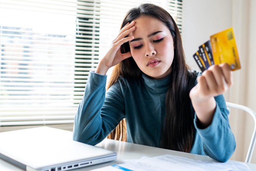 unhappy-girl-holding-three-credit-cards-feeling-s-2025-01-29-02-45-42-utc A woman looks stressed over her credit cards